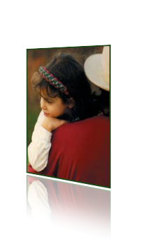 Photograph of the back of a man with a hat on. He holds a young girl girl dressed in ethnic festival garb who rests her chin on her hand which rests on his shoulder as she gazes in another direction than he. Child On Father's Shoulder